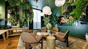 Ein Zimmer mit Rattanmöbeln, hängenden Pflanzen und Blick auf die Stadt.