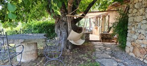 A rustic outdoor seating area with a stone table, metal chairs, and a hammock. - Provencal house with private pool 2 persons (MONS)