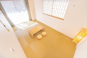 A room with tatami flooring, a low wooden bench, two tatami mats, a shoji screen, and a wall-mounted light fixture. - Luxury 2BR,2-toilet home! Theater,full kitchen,kids' room & garage.Family-ready! (Sumida City)