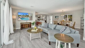 A spacious living area with a sofa, coffee table, and dining table. A kitchen is visible in the background. - Heated Pool Complimentary - Mini - Golf - Bicycles - Just 6 Minutes to the Beach (Fort Lauderdale)