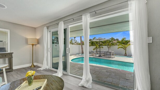 A room with a pool, white curtains, a table with a tray, and a lamp. - Heated Pool Complimentary - Mini - Golf - Bicycles - Just 6 Minutes to the Beach (Fort Lauderdale)