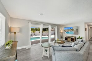 Una sala moderna con vistas a la piscina, un sofá, un televisor y una lámpara.