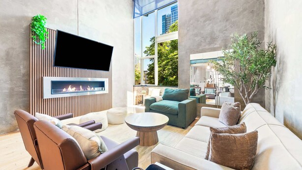 A modern living room with a fireplace, comfortable seating, and a large window offering a view of the city.