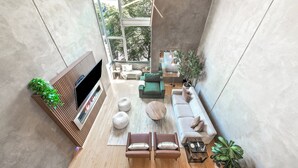 A modern living room with a flat-screen TV, a sofa, a coffee table, and a dining area with a table and chairs.