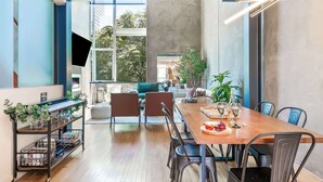 A modern dining area with a wooden table, black chairs, and a TV mounted on the wall.