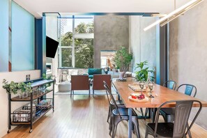 A modern dining area with a wooden table, black chairs, and a TV mounted on the wall.