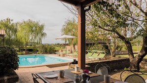 Ein Poolbereich mit einem Tisch für zwei Personen, einem Stuhl und Blick auf den Pool und die umliegende Bepflanzung.