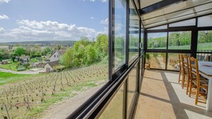 Interior moderno com grandes janelas que oferecem vista para um vinhedo.