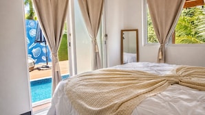 Un dormitorio con cama, ventana y vista a una piscina.