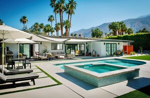 Une maison moderne dotée d’une piscine, de mobilier d’extérieur et offrant une vue sur les montagnes.