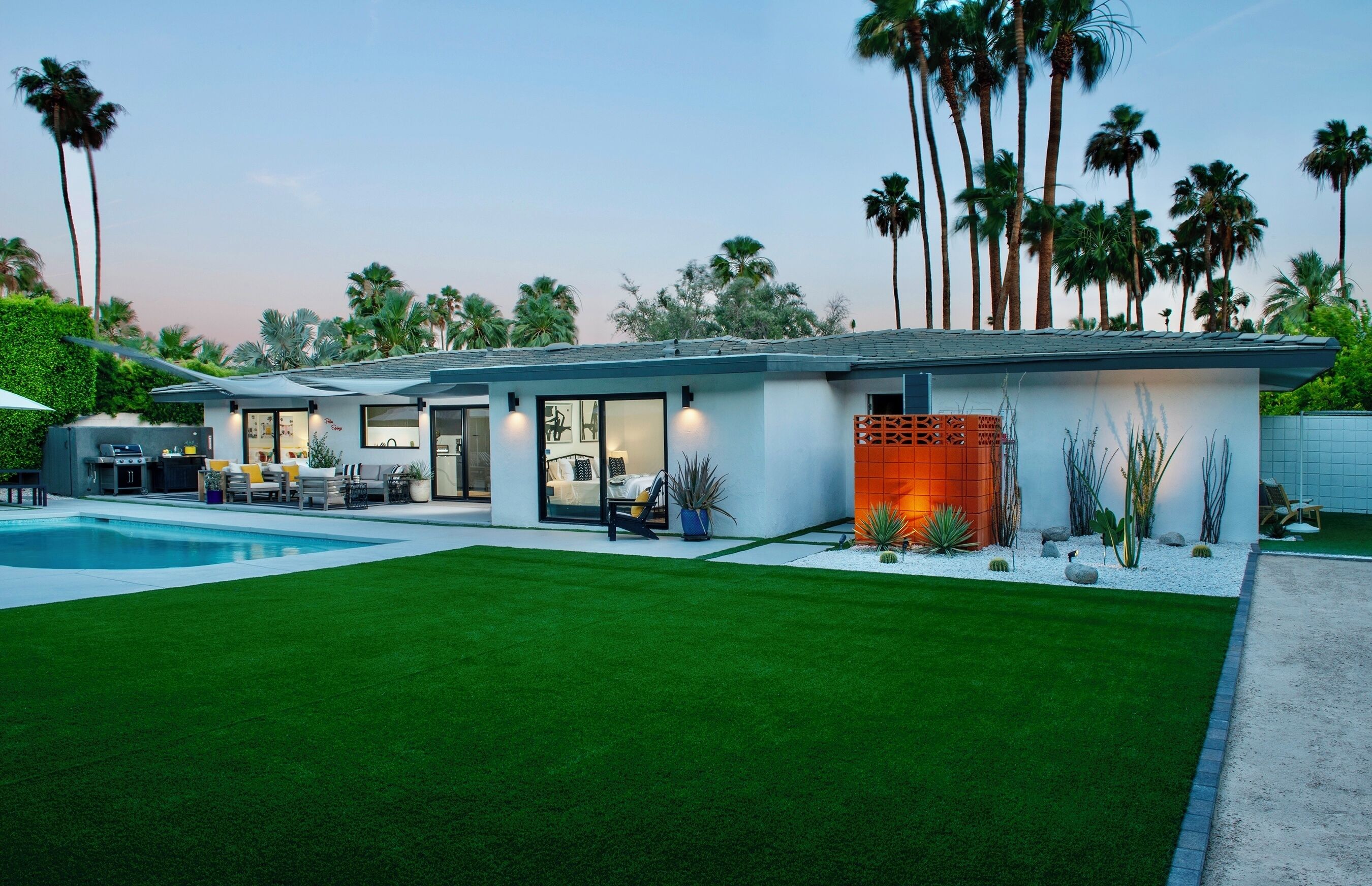Une maison moderne dotée d’une piscine, d’un espace extérieur aménagé et d’une pelouse bien entretenue.