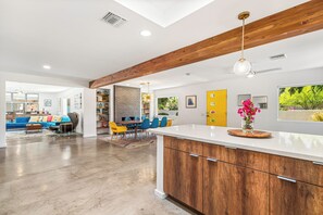 A modern kitchen with wooden cabinets, a white countertop, and a hanging light fixture. - Palm Springs Golden - Your Adventure Awaits! (Palm Springs)