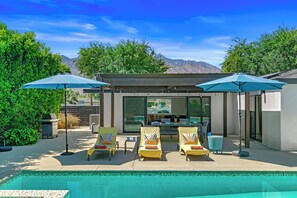 A poolside area with lounge chairs and umbrellas, a covered seating area, and a view of mountains. - Palm Springs Golden - Your Adventure Awaits! (Palm Springs)