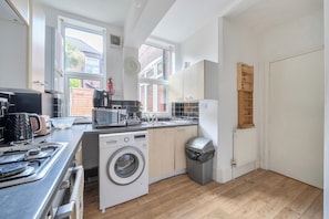 A compact kitchen with a washing machine, a stove, and a microwave.