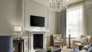 Una sala de estar con chimenea, televisor montado en la pared, candelabro y un sofá.