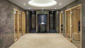A spacious hallway with a central decorative column, wooden doors, and a modern ceiling light fixture. - Ensana Buxton Crescent (Buxton)