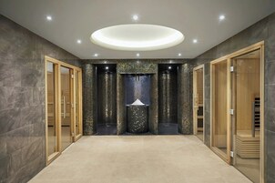 A spacious hallway with a central decorative column, wooden doors, and a modern ceiling light fixture.