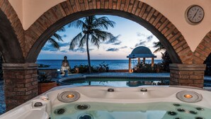 A hot tub with a view of the ocean and palm trees. - Oceanfront Villa w/ Private pool, private oceanfront access & sunset views (Kralendijk)