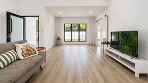 Un salon moderne avec un canapé, un téléviseur à écran plat et une grande fenêtre.