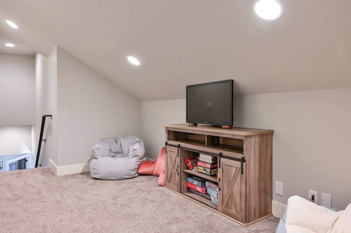 A room with a television on a wooden cabinet, a bean bag chair, and a bookshelf.
