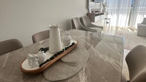 Ett modernt matområde med ett bord i marmor, vitt porslin och en tv som är monterad på väggen.