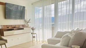 Ett modernt vardagsrum med en soffa, ett soffbord och en tv som är monterad på väggen.