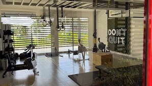 Ett modernt gym med olika typer av träningsutrustning, stora fönster och ett inspirerande citat på väggen.