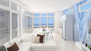 Eine moderne Küche mit großen Fenstern, einem Essbereich und einem Wohnraum mit Sofa und Kissen.