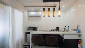 A compact kitchenette with a microwave, coffee maker, and a small refrigerator. There are two chairs and a fire extinguisher mounted on the wall. - La Palma Suite 1 with outdoor tubs and jacuzzi (Añasco)
