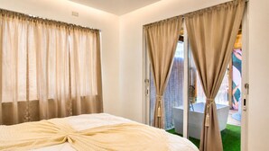 A hotel room with a bed, curtains, a view of a pool, and a door leading to a balcony. - La Palma Suite 1 with outdoor tubs and jacuzzi (Añasco)