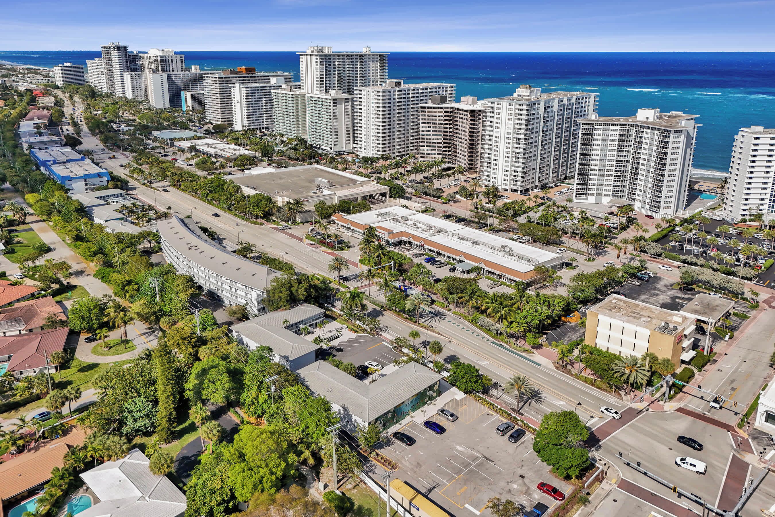 A high-rise hotel with multiple floors, a parking lot, and a view of the ocean.