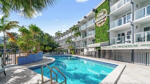 Un hotel con piscina, palmeras y un letrero que dice 'The Greenhouse Terrace Restaurant & Cafe'.
