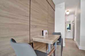 A modern hotel room with a wooden accent wall, a small table with a remote control, and a chair. - Ocean Blvd's Bright King Suite (Fort Lauderdale)