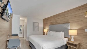 Una camera d'albergo moderna con un letto grande, lampade sui comodini, una scrivania con una sedia e una TV a parete.