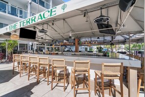 An outdoor bar area with wicker chairs and a bar counter, under a marquee with 'THE TERRACE' written on it. - Botanica King Studio Near Beach (Fort Lauderdale)