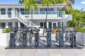 Ein modernes Gebäude mit Balkon, Treppe und einer Reihe von Ladestationen für E-Bikes.