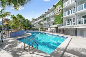 Ein Hotel mit Pool, Palmen und einem Schild für das Restaurant und Café 'The Greenhouse Terrace'.