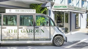 Un furgone bianco con la scritta 'The Garden Hotel & Resort', parcheggiato di fronte a un edificio con una reception.