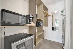 Eine Küchenzeile mit Mikrowelle, Kaffeemaschine und kleinem Kühlschrank.