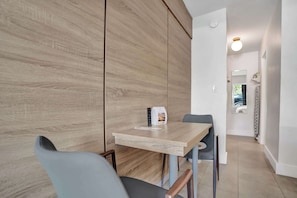 Ein modernes Hotelzimmer mit einer Wand in Holzoptik, einem kleinen Tisch mit Fernbedienung und einem Sessel.