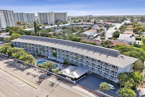 A modern hotel with a curved roof, multiple floors, and a swimming pool. - Ocean Blvd Two Double Suite Kitchenette at The Botanica (Fort Lauderdale)