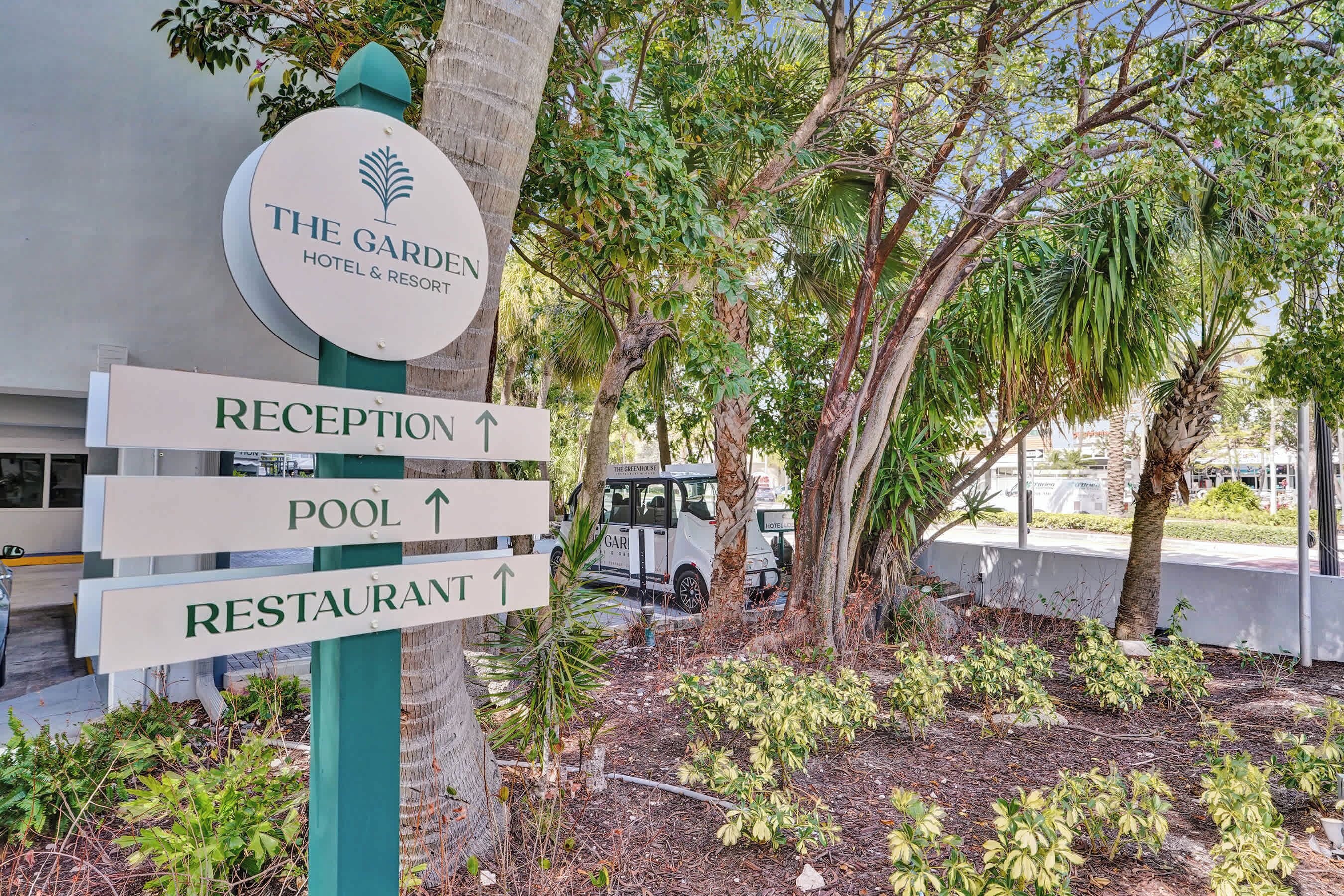 A sign for The Garden Hotel & Resort with directions to the reception, pool, and restaurant.