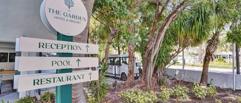 Un panneau indiquant l’hôtel et le complexe hôtelier « The Garden Hotel & Resort », avec des indications pour se rendre à la réception, à la piscine et au restaurant.