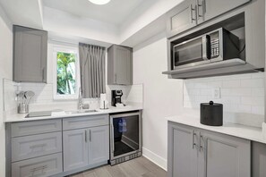 A modern kitchen with grey cabinets, a built-in microwave, a coffee machine, and a mini-fridge. - Ocean Blvd Two Double Suite Kitchenette at The Botanica (Fort Lauderdale)