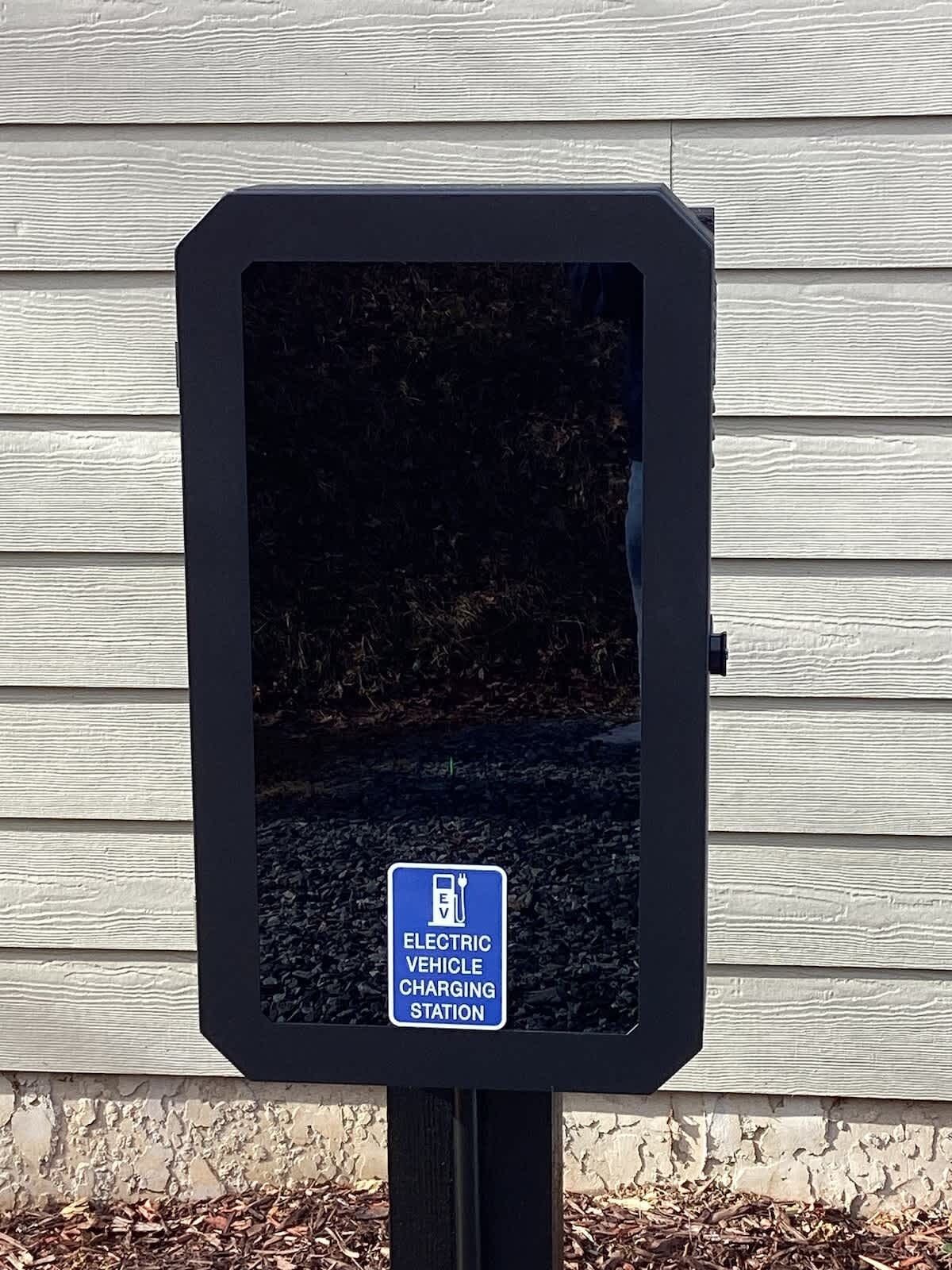 An electric vehicle charging station sign on a post.