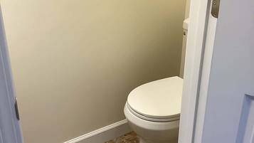 Ein Badezimmer mit Toilette, beige Wänden und braunen Fliesen.