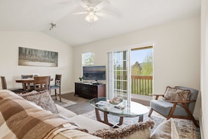 A living room with a sofa, coffee table, TV, and a balcony with a view.