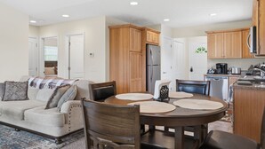 Un espacio habitable compacto con comedor, kitchenette y un sofá con manta.