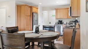 Una cocina moderna con armarios de madera, un refrigerador de acero inoxidable y un comedor con una mesa redonda y sillas.