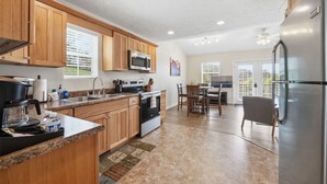 Una cocina con armarios de madera, microondas, estufa y refrigerador.
